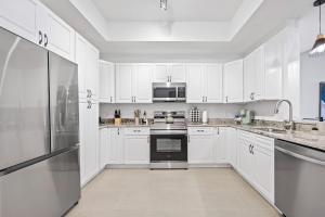 RIVER FLY-IN Luxury Condo w Views & Amenities RFI-1003 في Audubon: مطبخ أبيض مع خزائن بيضاء وأجهزة
