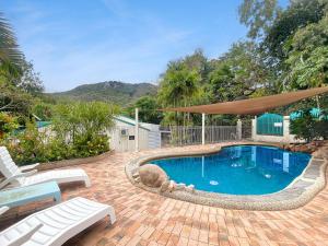 una piscina con ombrellone e sedie su un patio di Magnetic Reef 5 ad Arcadia