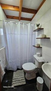 Un baño con una cortina de ducha blanca y un inodoro. en Cabaña Panguipulli - Sector Altos de Palguin, en Panguipulli