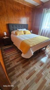 Un dormitorio con una cama grande con una pared de madera. en Cabaña Panguipulli - Sector Altos de Palguin, en Panguipulli