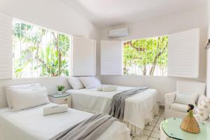 two beds in a room with two windows at Casa a 100 metros do mar- no Centro de Porto de Galinhas in Porto De Galinhas +57 photos