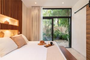 Chic Villa-Apartment in Aldea Zama, Private Pool & Security في تولوم: غرفة نوم بها سرير ونافذة كبيرة