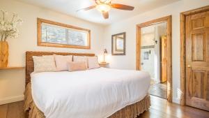 a bedroom with a white bed and a ceiling fan at Hot Tub Fire Pit Game Room Large Deck Views Angels Camp Lodge by AvantStay in Big Bear Lake