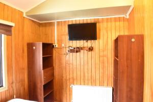 Una habitación con un televisor en una pared de madera. en Cabañas Mister Nelson, en Valdivia