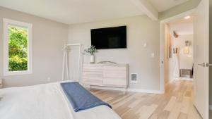 a white bedroom with a bed and a tv on the wall at Sunset Cove by AvantStay Beachfront w Balcony in Arch Cape