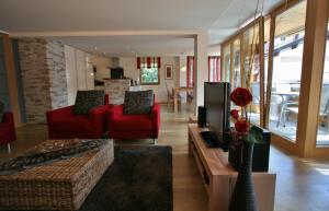 Sala de estar con 2 sillas rojas y TV en Landhaus Alpenflair Whg 310 en Oberstdorf