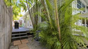 Un patio con palmeras al lado de un edificio. en Paradise Palms by AvantStay Great Location w Outdoor Dining BBQ Close to Higgs Beach Month Long Stays, en Key West