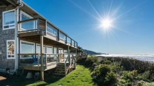 a house on the beach with the sun in the sky at Blue Starfish by AvantStay Ocean Views Direct Cannon Beach Access in Cannon Beach