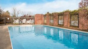 a swimming pool with blue water in front of a brick building at River House by AvantStay Historic Secluded Estate on the Hudson River w Pool Sleeps 24 in Hudson