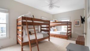 two bunk beds in a room with a ceiling fan at Poseidon By AvantStay On The Beach Two Ocean Facing Balconies Hot Tub in Folly Beach