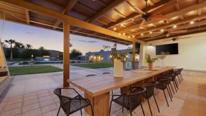 an outdoor dining area with a wooden table and chairs at Sleeps 20 Architectural Mansion w Pool Indoor Tennis Court Game Room Starlight Estate by AvantStay in Bermuda Dunes