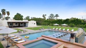 a swimming pool with lounge chairs and a house at Sleeps 20 Architectural Mansion w Pool Indoor Tennis Court Game Room Starlight Estate by AvantStay in Bermuda Dunes