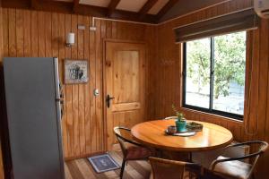 Una pequeña cocina con una mesa y un refrigerador. en Cabañas Mister Nelson, en Valdivia