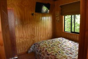 Un dormitorio con una cama y una ventana en Cabañas Mister Nelson, en Valdivia