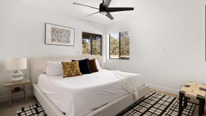 a white bedroom with a bed with a ceiling fan at Roca Roja by AvantStay Mountain Views in the Heart of Sedona in Sedona