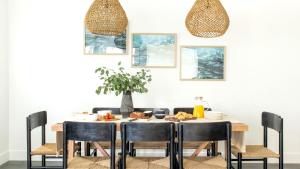 a dining room table with black chairs and a table with food on it at ONeill I by AvantStay Coastal Paradise Steps from Beach Modern Decor in Newport Beach
