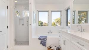 uma casa de banho branca com 2 lavatórios e um chuveiro em Emerald Cove by AvantStay Mins to Beach Pier em Newport Beach mais 29 fotografias