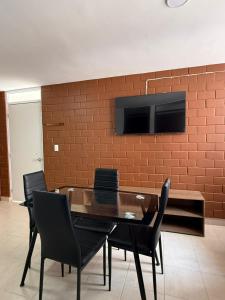 a dining room table with chairs and a television on a brick wall at Departamento Villas Doradas in Santa Cruz Huatulco