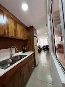 a kitchen with wooden cabinets and a sink and a living room at Departamento Villas Doradas in Santa Cruz Huatulco