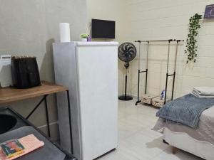 コチアにあるKitnet em Cotia perto Animalia Park CT do Sao Pauloの白い冷蔵庫、ファンが備わる客室です。
