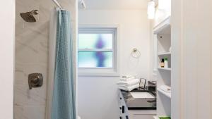 a bathroom with a shower with a blue shower curtain at Sunny Side Island Retreat by AvantStay Backyard in Freeland +37 photos
