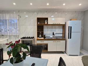 a kitchen with a refrigerator and a table with a plant at Apartamento 8min da praia e 11 do Beto Carrero in Penha