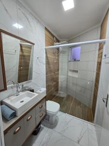 a bathroom with a sink and a toilet and a shower at Apartamento 8min da praia e 11 do Beto Carrero in Penha