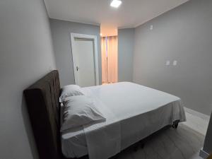 a bedroom with a large bed with white sheets at Apartamento 8min da praia e 11 do Beto Carrero in Penha