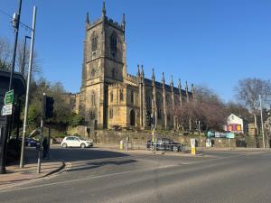 een oude kerk met een klokkentoren op een straat bij Sowerby Homes in Sowerby Bridge
