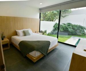 a bedroom with a large bed and a large window at Casa Begonias Hotel mas Villas in Jiutepec