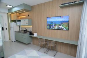 a kitchen with a counter with two chairs and a tv on the wall at Green One - Em Frente à Estação Luz com vaga rotativa in Sao Paulo