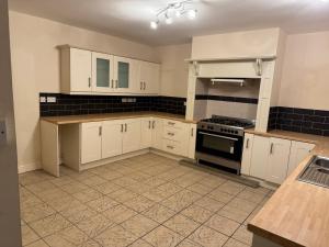 een keuken met witte kasten en een kookplaat oven bij Sowerby Homes in Sowerby Bridge