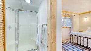 Cove Cottage by AvantStay Waterfront Views Spa في كوبيفيل: حمام مع دش وسرير في الغرفة +26 صورة