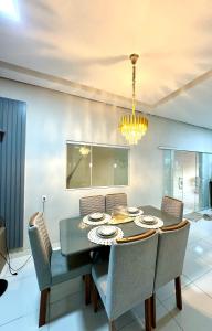 een eetkamer met een tafel, stoelen en een kroonluchter bij Brisa das dunas in Tutóia