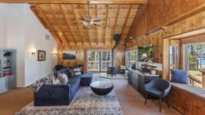 een woonkamer met een blauwe bank en een plafondventilator bij Lakefront Dock Hot Tub Swingset Deck Views Classic Lake House by AvantStay in Big Bear Lake