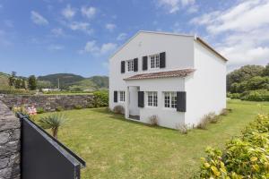 una casa blanca con patio y pared en Casa das Camélias - Family Villa by the lagoon en Sete Cidades