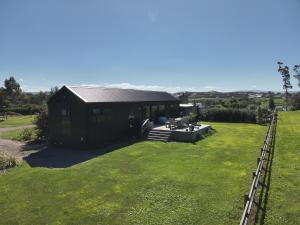 a small black house with a grass yard at Kotuku Cottage in Tauranga