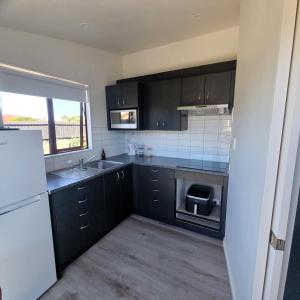 a kitchen with black cabinets and a sink at Margaret Home in Christchurch