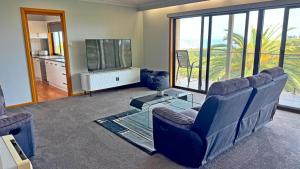 a living room with couches and a tv and a balcony at Ocean Views on Lyrebird in Lakes Entrance