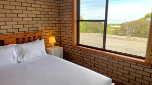 a bedroom with a bed and a brick wall at Ocean Views on Lyrebird in Lakes Entrance