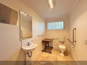 Un baño con lavabo, inodoro y espejo. en Neat 1BR - AC & Parking, en Moranbah