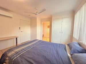 Un dormitorio con una cama y un ventilador de techo. en Neat 1BR - AC & Parking, en Moranbah