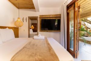 a bedroom with a large bed and a tv at Suíte Charmosa na Mucugê - Café da manhã opcional - Conforto e Localização Perfeita in Porto Seguro