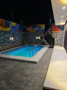 een zwembad met een schilderij aan de muur bij bedandchuckle in Kaduna