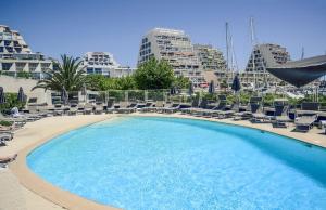 una gran piscina con tumbonas y un edificio en Mercure Port La Grande Motte, en La Grande-Motte