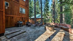 an outdoor patio with a fireplace and a house at Moosetrack by AvantStay Cozy Cabin w Hot Tub In The Heart of Tahoe Donner in Truckee
