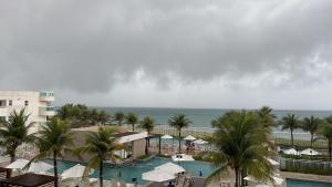 a view of a pool with palm trees and the ocean at In mare Bali Resort in Parnamirim