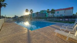 a swimming pool with two white chairs and palm trees at Studio w Balcony Pools Direct Beach Access Seaside Blessing by AvantStay in Port Aransas