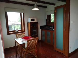 a kitchen with a table and chairs and a microwave at T0 Eira Frente in Vieira do Minho