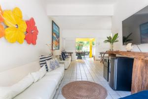a living room with a white couch and a tv at Casa a 100 metros do mar- no Centro de Porto de Galinhas in Porto De Galinhas